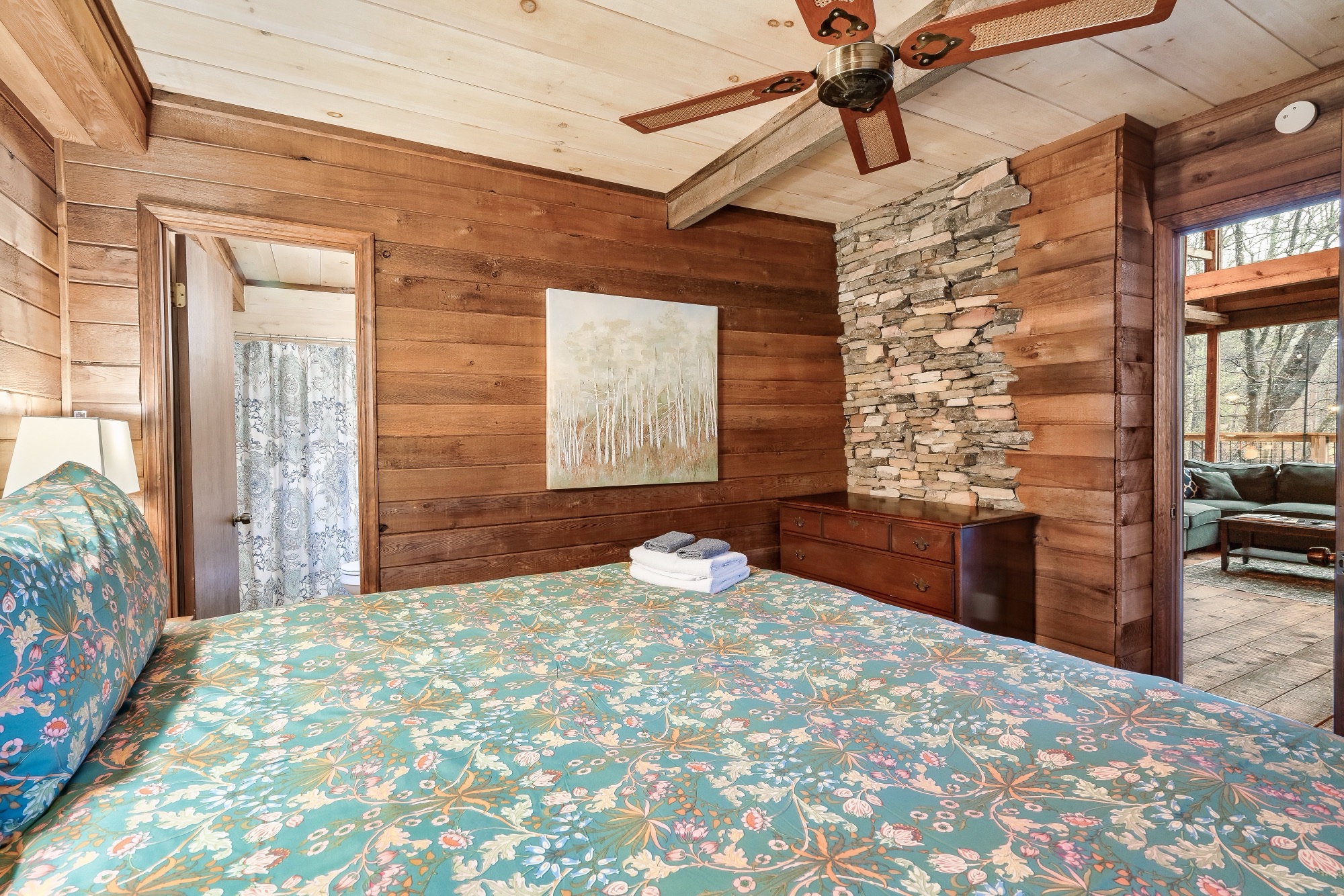 Primary bedroom at Rustic Retreat with a stone accent pillar and access to the private bathroom and deck